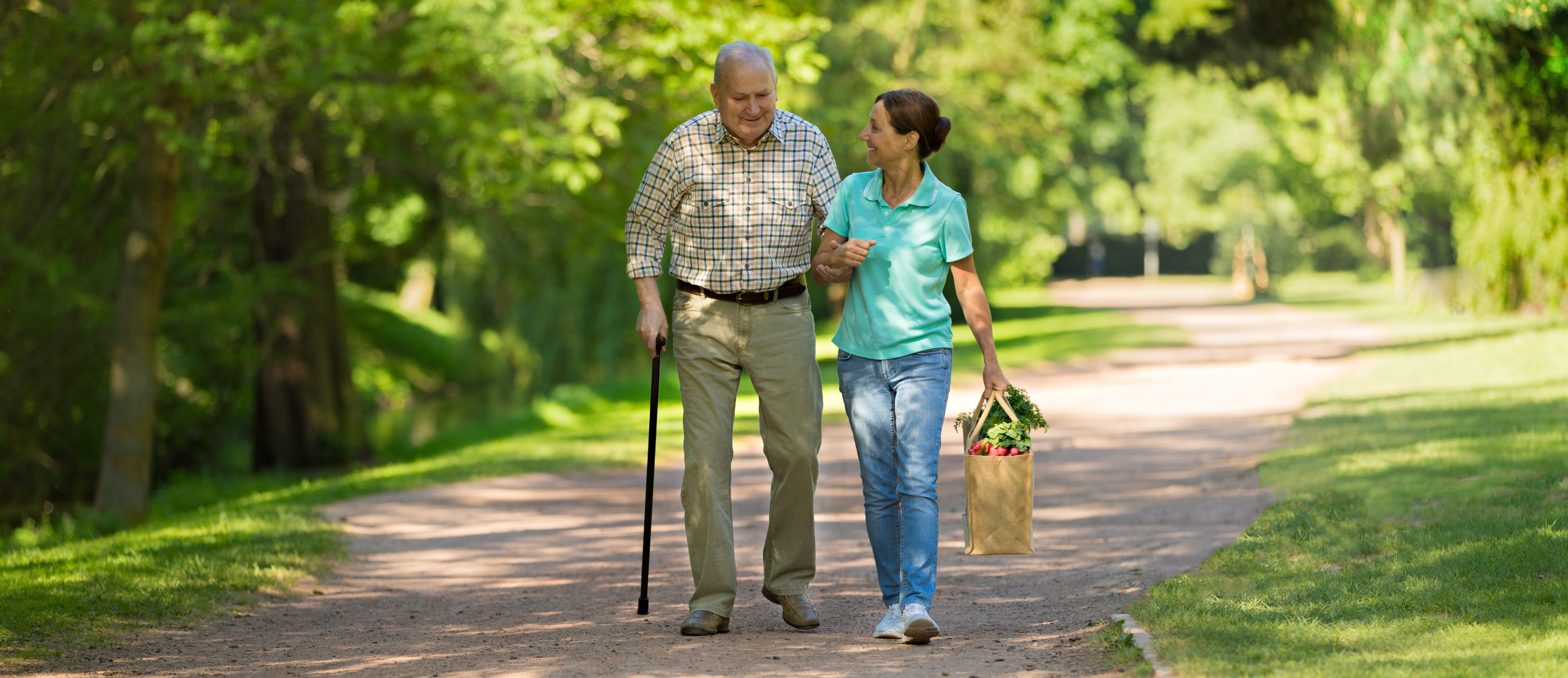 Caregiver – woman helping senior man outdoors in the park